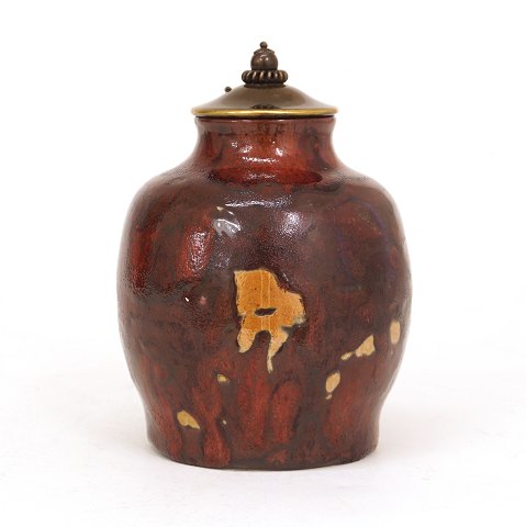 Patrick Nordström, 1870-1929, for Royal 
Copenhagen: Vase i stentøj med okseblodsglasur med 
gul/brune aftgegninger og originalt bronzelåg. 
Signeret Patrick Nodström 07.06.1918. H: 16,8cm