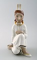 Rare Arno Malinowski for Royal Copenhagen.
Seated girl with headwear. Overglaze.