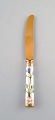 Michelsen for Royal Copenhagen. "Flora Danica" lunch knife of gold plated 
sterling silver. Porcelain handle decorated in colors and gold with flowers.