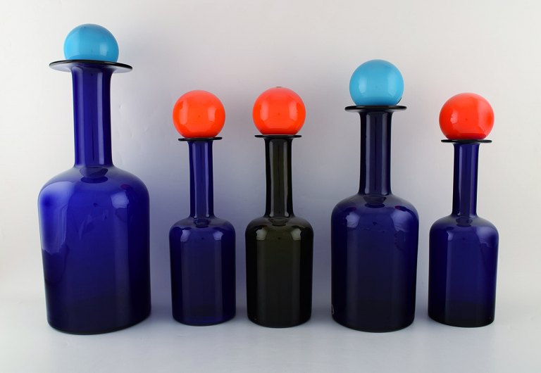 Otto Brauer for Holmegaard. A collection of five large vases / bottles in dark 
blue and green art glass with lids in the shape of a ball. 1960