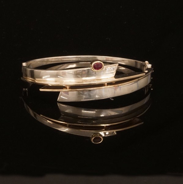 A 14kt gold and sterlingsilver bangle with two diamonds of ca. 0,08ct. Size: 
6,6x6cm