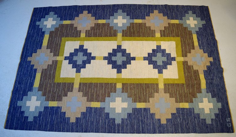 Swedish textile designer. Large hand-woven RÖLAKAN rug in pure wool with 
geometric fields in olive green, brown, blue, and sand-colored shades. Mid-20th 
century.
