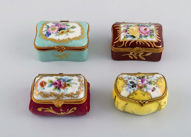 Limoges, France. Four small porcelain lidded chests with hand-painted flowers 
and gold decoration. Early 20th century.
