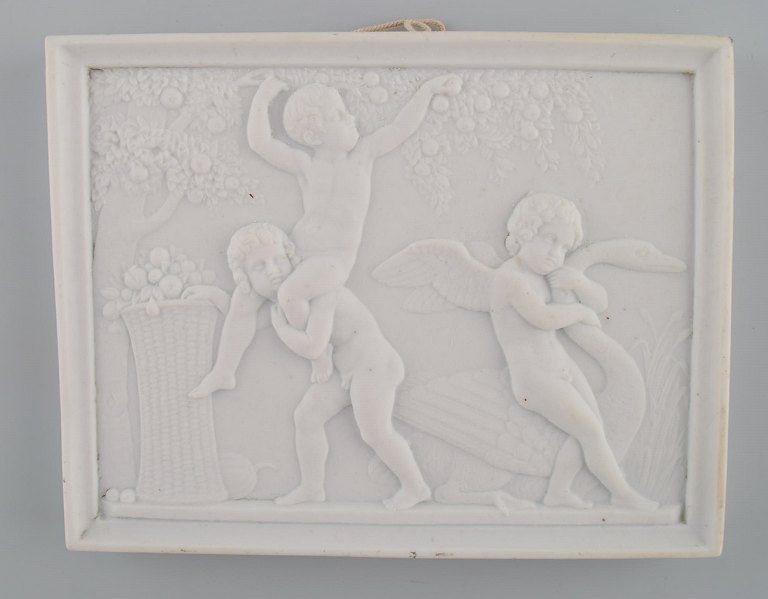 Bing and Grøndahl after Thorvaldsen. Antique biscuit wall plaque with putis and 
swan in relief. 1870s / 80s.
